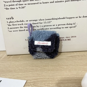 Detailopname van blauw pluche koptelefoonhoesje met merklabel op houten blad