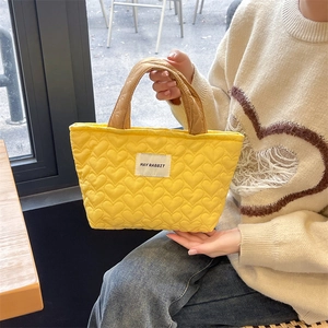 Detail of yellow quilted heart tote bag featuring a MAY RABBIT logo and brown padded handles