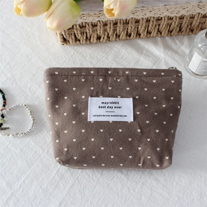 Detailed view of a brown polka dot heart makeup bag with zipper and logo label