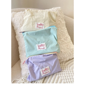Three-piece macaron cosmetic bag set in beige, mint green, and lilac with woven labels