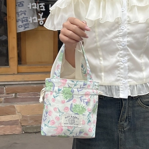 Close-up of floral drawstring canvas bag with May Rabbit logo and pink rose patterns