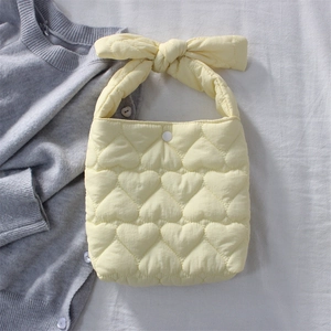 Detail of light yellow quilted heart pattern bag with large decorative bow handle