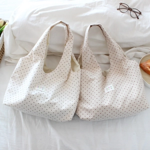 Detail of cream and brown canvas tote bags featuring red heart prints and brand labels