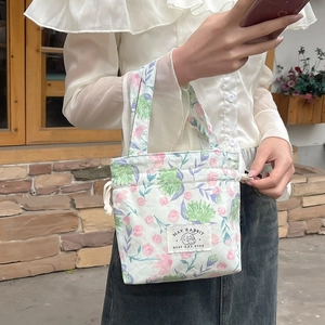 Close-up of floral drawstring handbag with MAY RABBIT logo label and sturdy handle