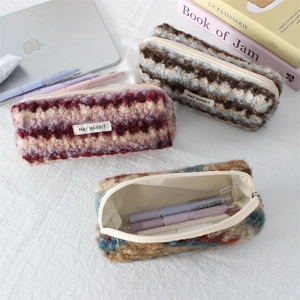 Close-up of three plush fuzzy pencil cases with top zippers and spacious interior storage