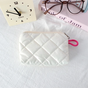 Close-up of white quilted coin purse with pink zipper pull and satin finish detail