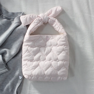Detailed close-up of pink quilted heart bag featuring a large bow handle and snap button