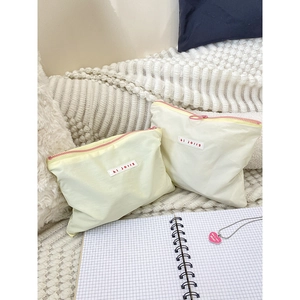 Set of two yellow macaron makeup pouches with pink zippers and hi jolly woven labels