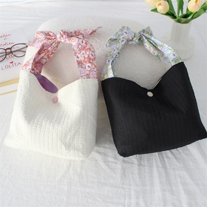 Detailed view of striped fabric tote bags with floral bow handles and button closure
