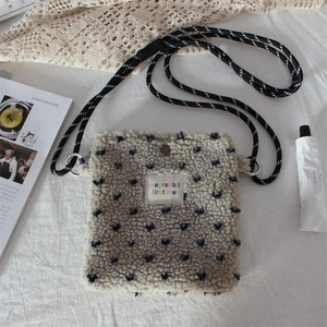 Detailed close-up of plush beige polka dot crossbody bag with woven shoulder strap