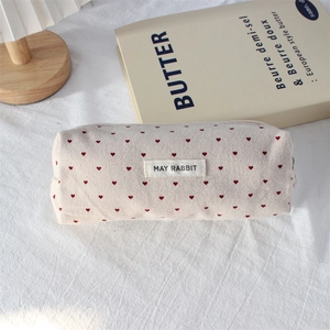 Detailed macro shot of the cream canvas fabric and red heart pattern on the pencil case