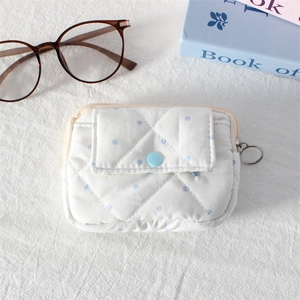 Detailed macro view of quilted mini pouch with blue polka dots and secure snap closure