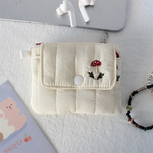 Detail of cream quilted mini pouch featuring a cute red mushroom embroidery and snap button
