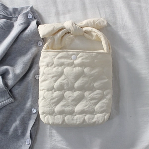 Detail of cream quilted handbag featuring heart embroidery and a soft bow handle design