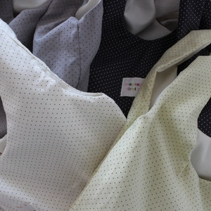 Close-up of lightweight polka dot tote bags in various colors on textured fabric