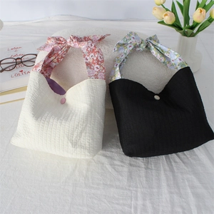 Detail of mini fabric tote bags with pleated texture and floral bow knot handles