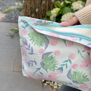 Close-up of floral makeup bag with blue zipper on stone background outdoors