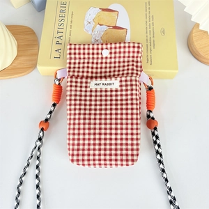 Detail of red checkered canvas phone bag with orange rope strap and logo label