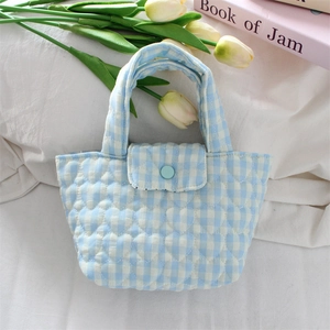 Detail of heart quilted blue gingham pattern and button closure on soft cotton handbag