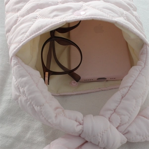 Light pink quilted puffer handbag with snap closure showing interior phone and glasses storage