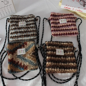 Detail of four colorful striped plush crossbody bags with soft faux fur texture and long straps