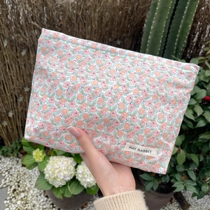 Detail of floral cotton makeup bag with May Rabbit label in a garden setting