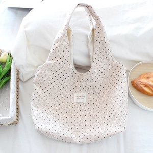 Close-up of heart print canvas tote bag featuring a white square woven brand label