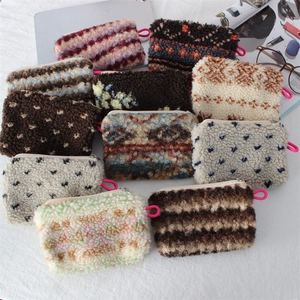 Flat lay of diverse plush makeup bags with colorful patterns and soft lamb wool texture