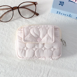 Close-up of pink quilted mini pouch with heart patterns and circular metal zipper pull
