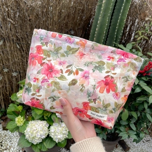 Detailed texture of a floral cosmetic bag held by hand in a natural garden setting