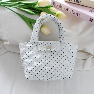 Close-up of heart-shaped quilted polka dot tote bag with button closure on white cloth