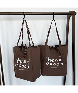 Detail of brown canvas tote bags featuring bold white hello print and floral lining