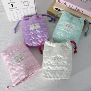 Detailed view of quilted heart pattern satin drawstring pouches in pastel colors
