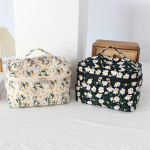 Detail of embroidered daisy cosmetic bags with sturdy dual zippers and top carry handles