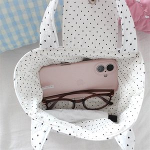 Internal storage detail of quilted polka dot handbag showing everyday essentials