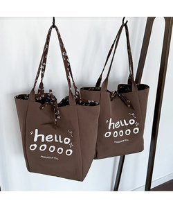 Detail of coffee canvas tote bag featuring floral lining and white printed lettering