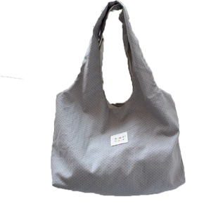 Grey tote bag with red polka dots and a wide shoulder strap in a minimalist casual style