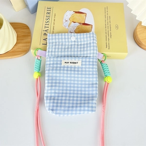 Close-up of blue plaid crossbody phone bag with pink strap and metal snap closure