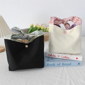 Detail of fabric tote bag with floral bow handles and textured vertical stripes