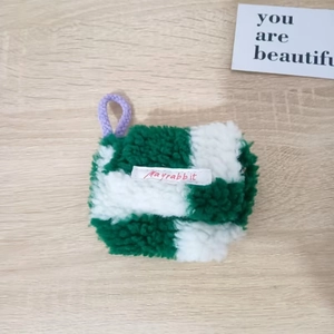 Detail van groen geruit pluche oortelefoonhoesje met paarse ophanglus voor opslag