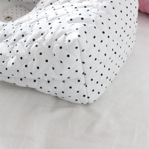 Close-up of heart-shaped quilting and black polka dots on white cotton handbag