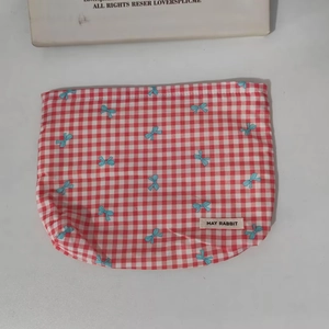 Close-up of red checkered fabric pouch with blue bows and May Rabbit label