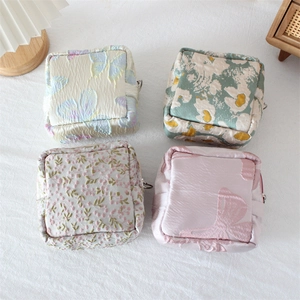 Macro view of four floral jacquard square pouches with elegant satin texture and zippers