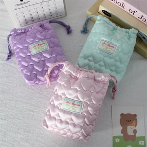 Detailed view of quilted heart drawstring pouches in pastel purple, mint, and pink colors