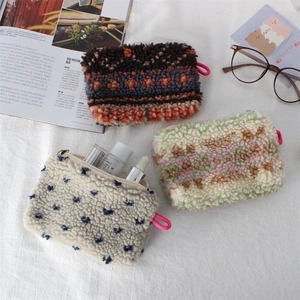 Three assorted plush cosmetic bags in geometric and floral patterns with zipper closure