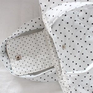 Close-up of white quilted handbag featuring heart stitching and magnetic snap closure