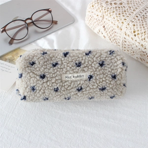 Detail of plush beige stationery bag featuring blue heart patterns and fabric label