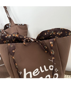 Detail of floral lining and white hello lettering on a dark brown canvas tote bag