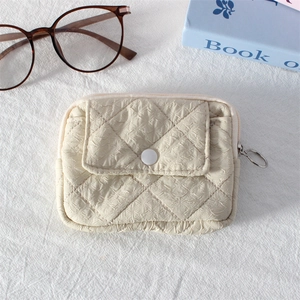 Close-up of beige quilted mini coin purse with metal zipper ring and snap front pocket