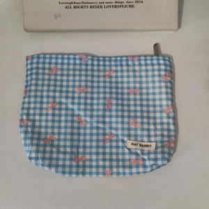 Detailed view of blue checkered makeup bag with pink bow pattern and zipper closure